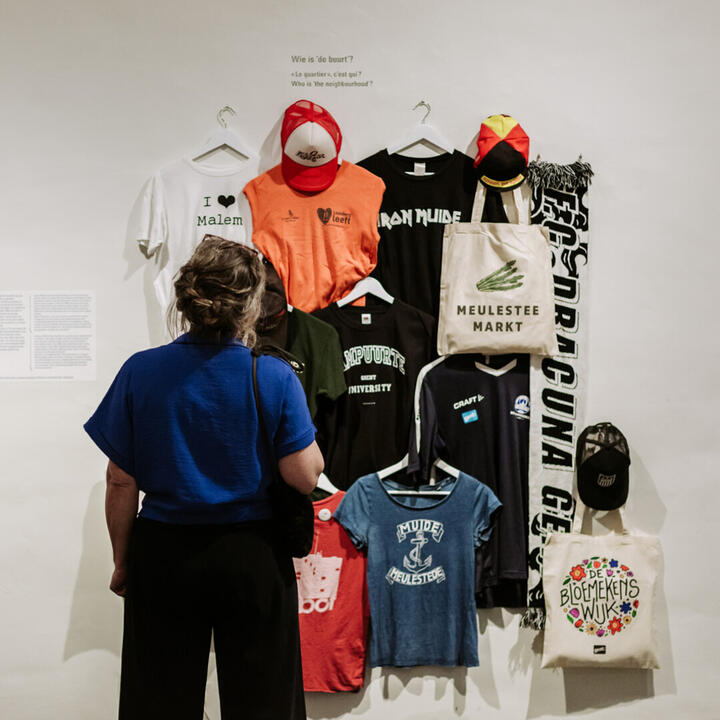 Een bezoeker bekijkt een van de exporuimtes van de expo 'De Poorten', vol merchandise uit de Gentse poortwijken.