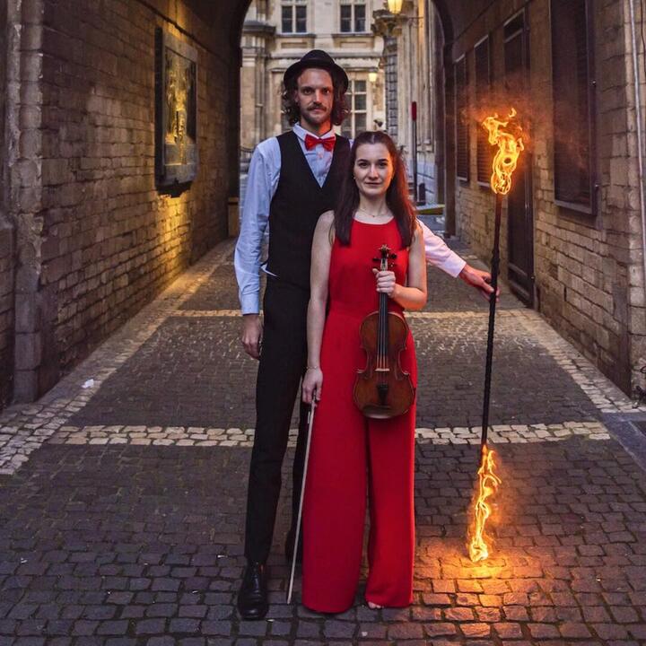 man en vrouw in een gang met vuurstok en viool