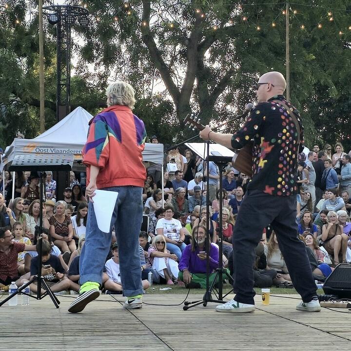 Een live optreden in de buitenlucht met twee muzikanten op het podium.