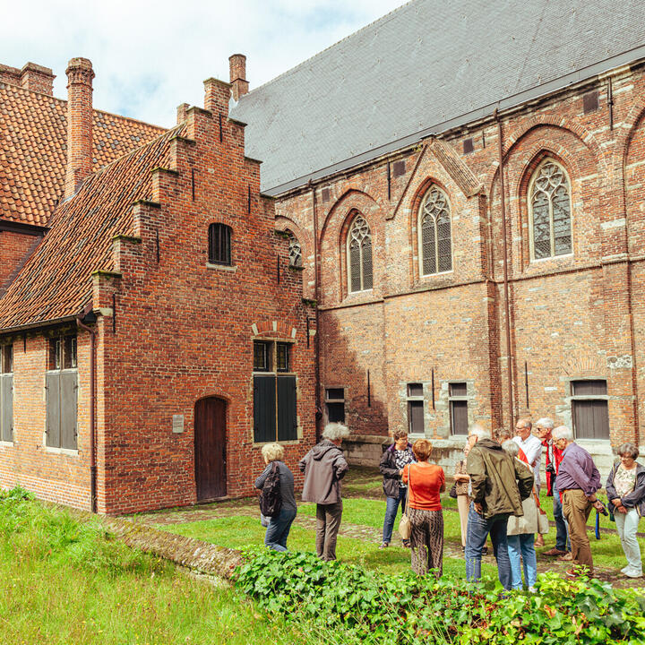 Een gids geeft uitleg in de tuinen rond het STAM tijdens een rondleiding over de zusters en de geschiedenis van de Bijlokesite.