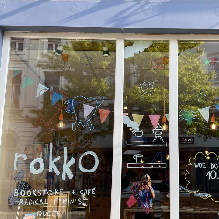 De gevel van rokko, een groot raam met boeken in de etalage en kleurrijke tekeningen in krijtstift