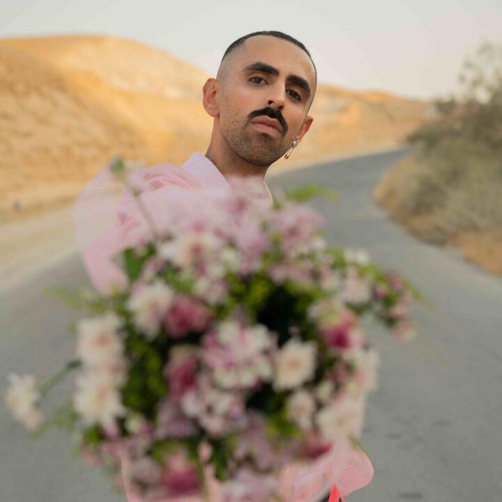 serieuze arabische man op een baan in de woestijn met bloemen