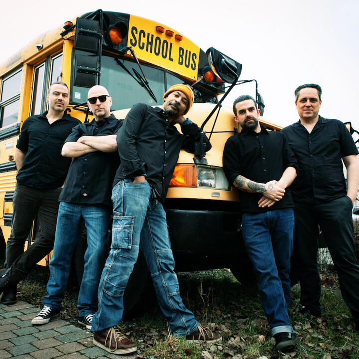5 mannen voor een oude gele schoolbus