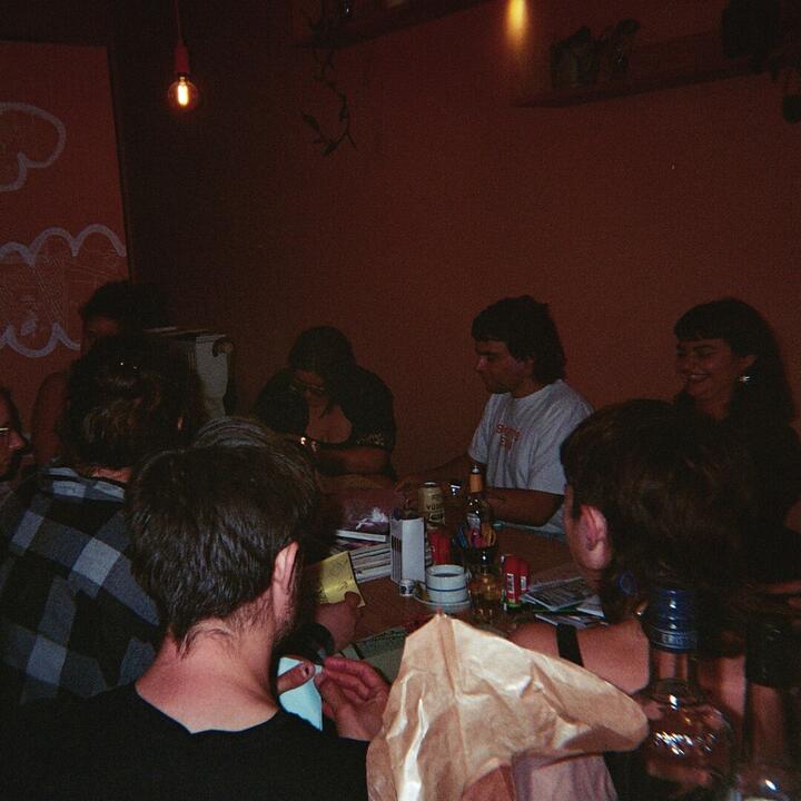 een groep mensen zit achteraan aan een lange tafel in rokko