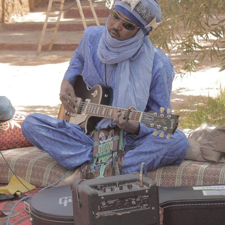touareg gitarist in traditionele nomaden kledij, met gitaar en versterker