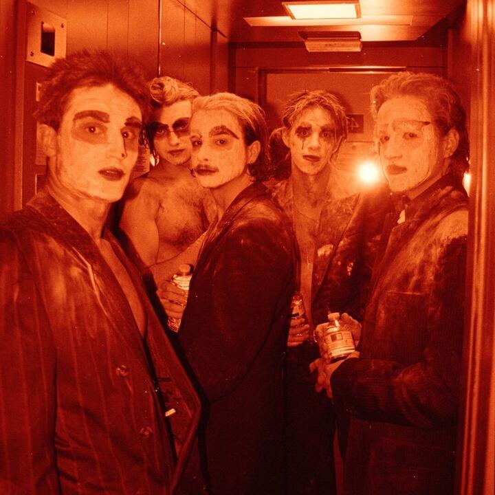 5 wit geschminkte mannen samen in een kleine lift
