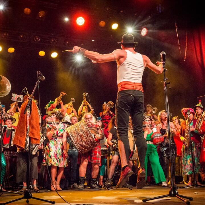 springende man met rond hem tientallen feestende muzikanten