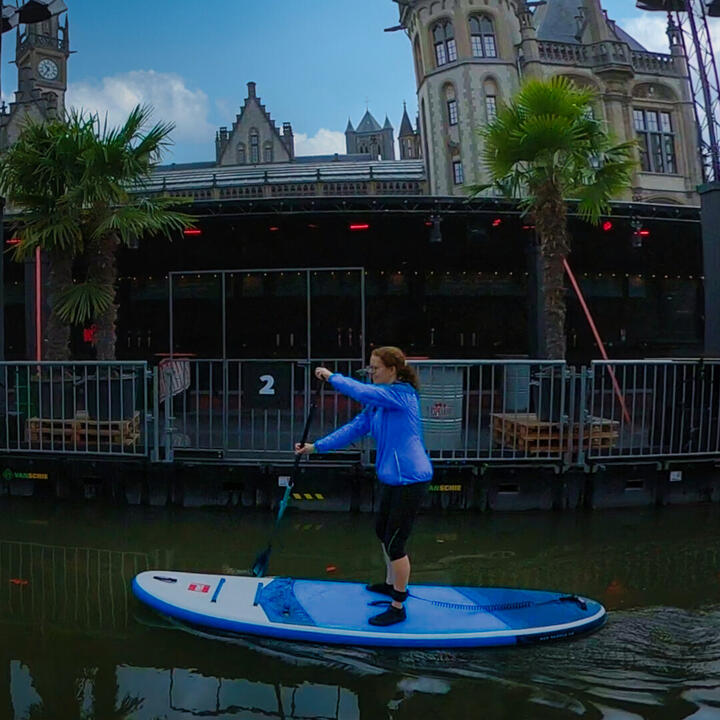 SUP deelnemer op een rustige vroege vogel sup tocht in Gent met historische gebouwen op de achtergrond