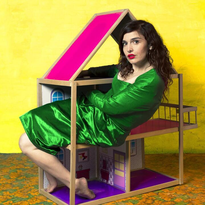 Nele met groene jurk in een roze poppenhuis met gele achtergrond