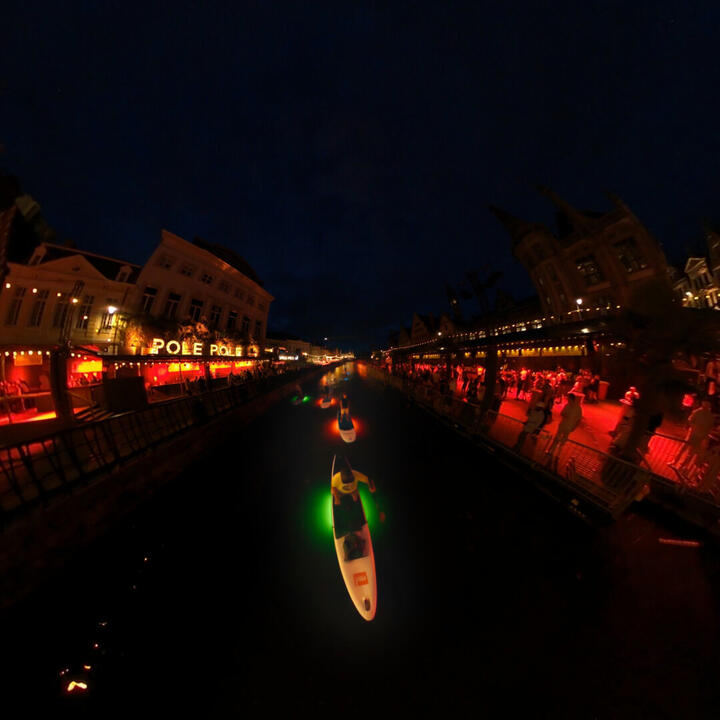 Unieke avond SUP ervaring in Gent tijdens de Gentse Feesten met verlichte paddle boards op het water, tussen feestende mensen en iconische gebouwen in het historische centrum