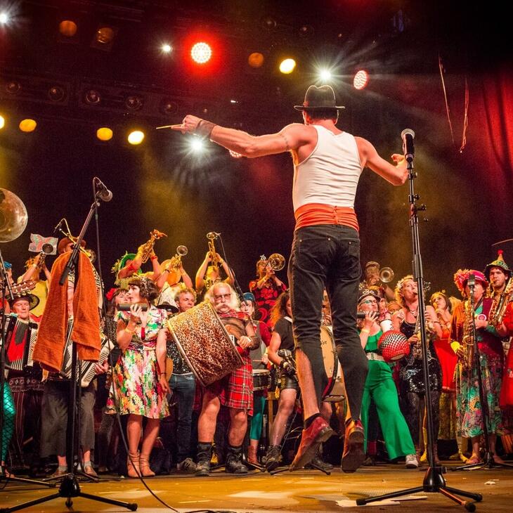 springende man met rond hem tientallen feestende muzikanten